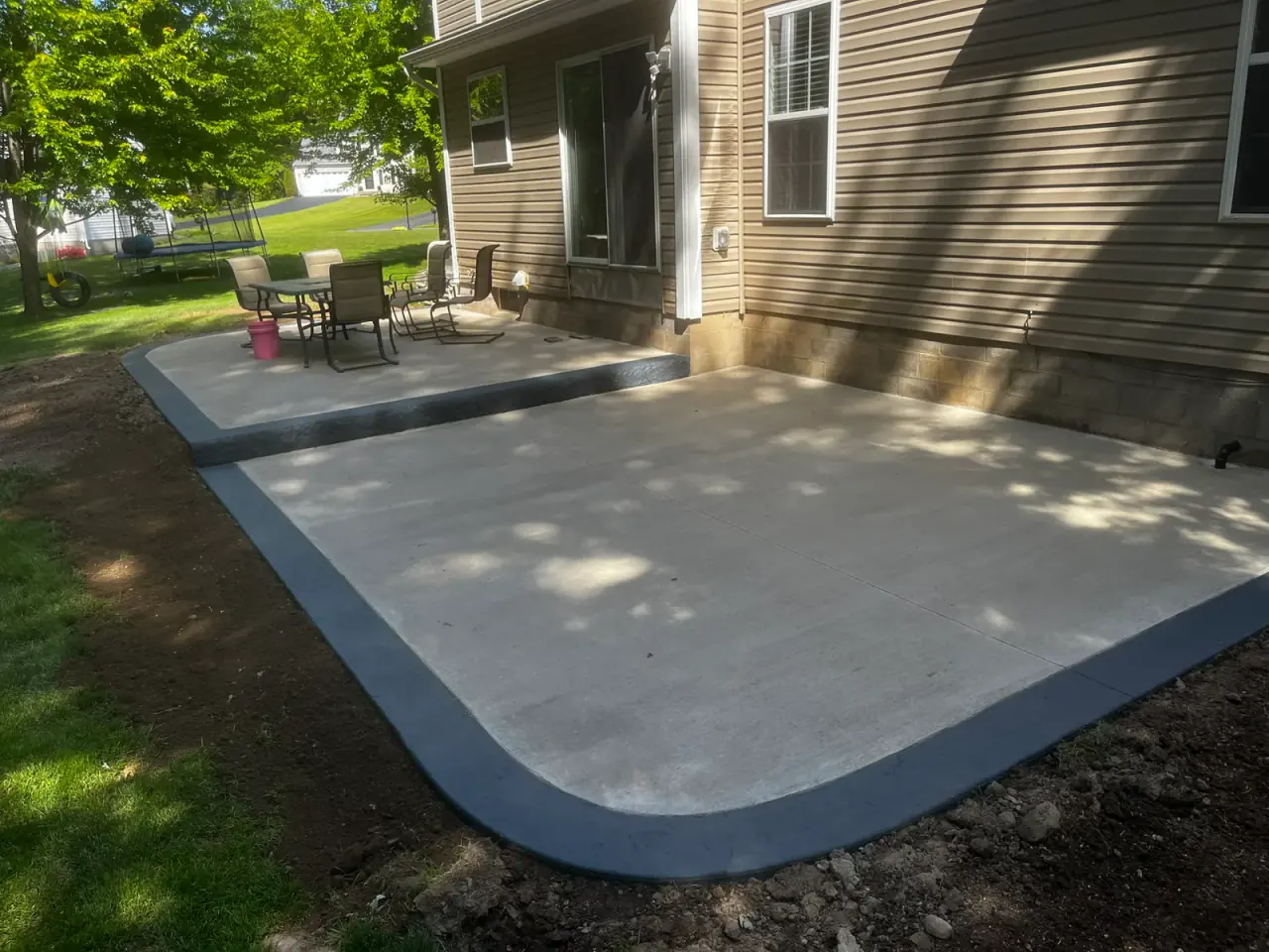 Two-level broom-finished concrete patio with a dark decorative border
